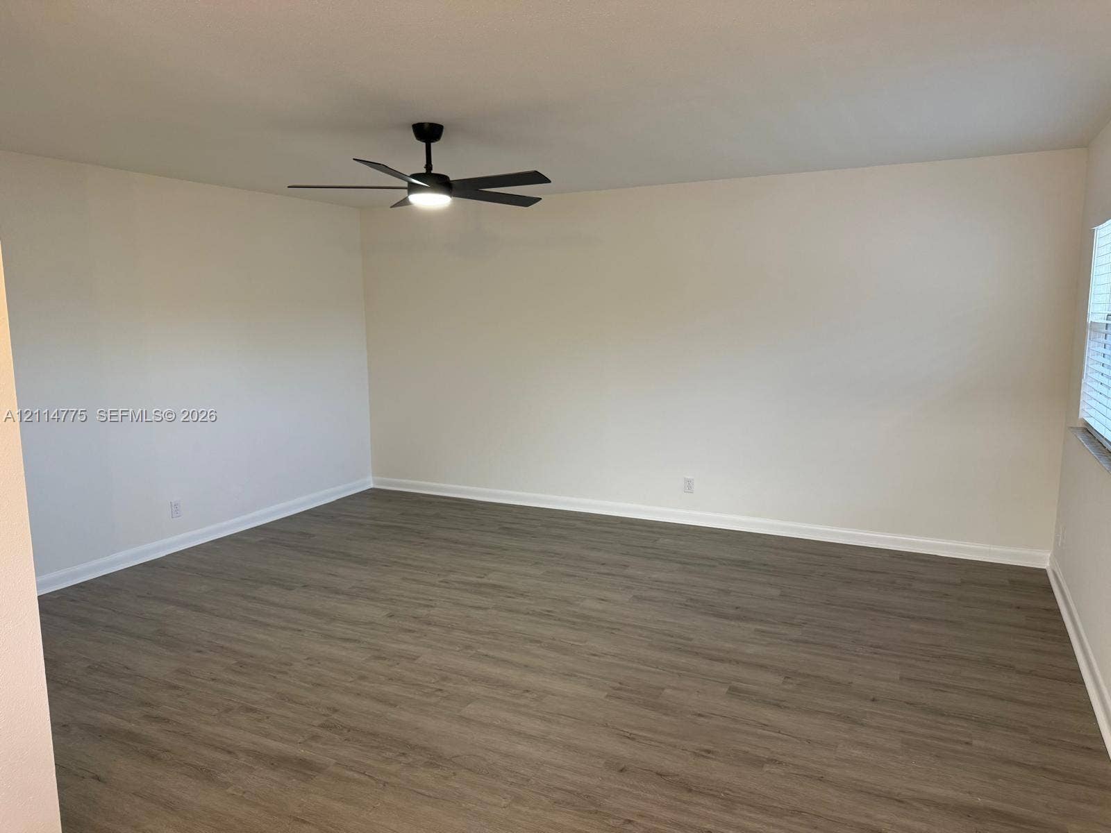 653 N Saxony N, #653, Delray Beach, FL 33446 Neutral-toned interior space featuring wood-finish flooring and a central matte black ceiling fan with integrated lighting