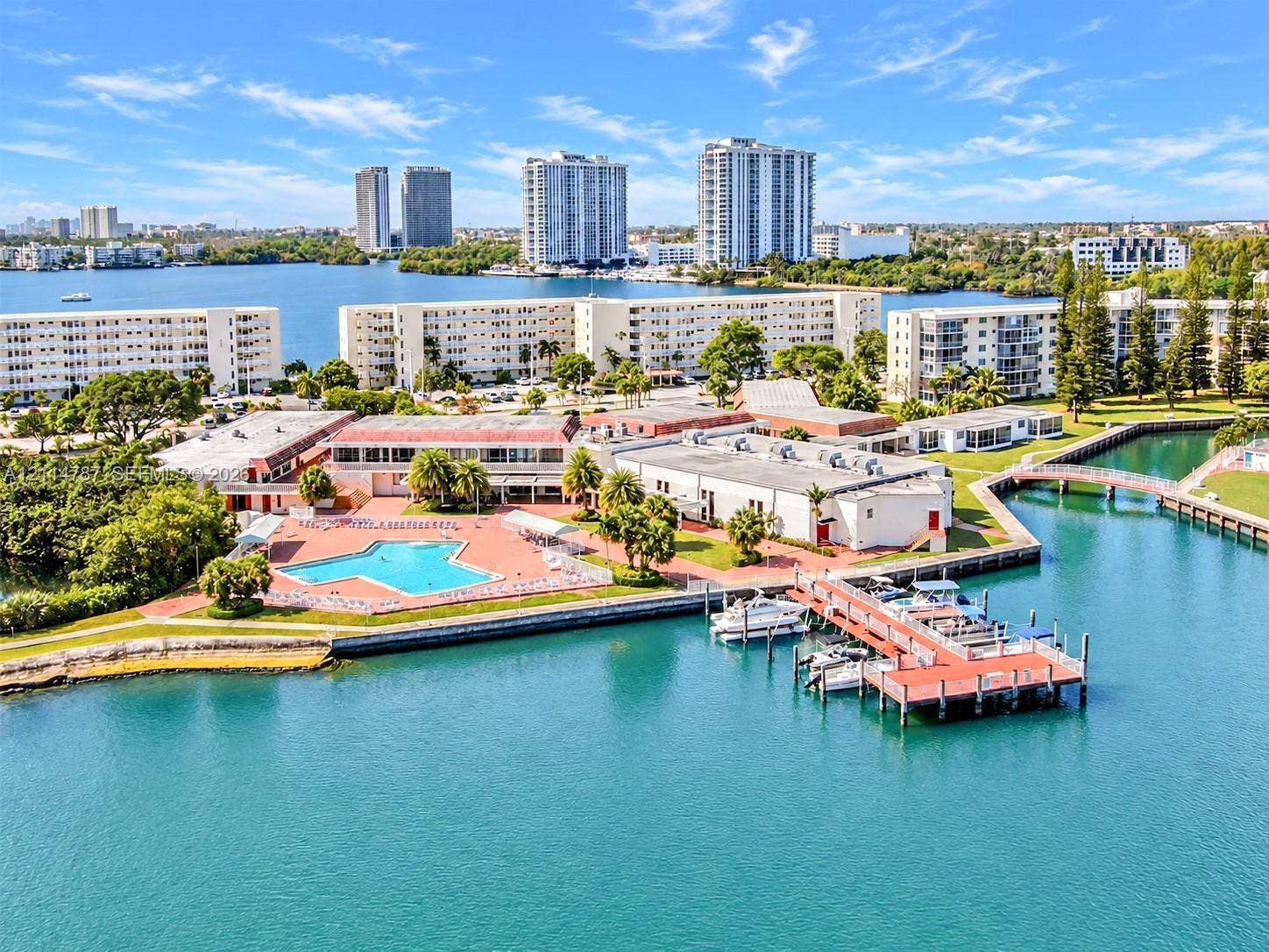 Waterfront property featuring a swimming pool, private boat dock, concrete seawall, and landscaped grounds