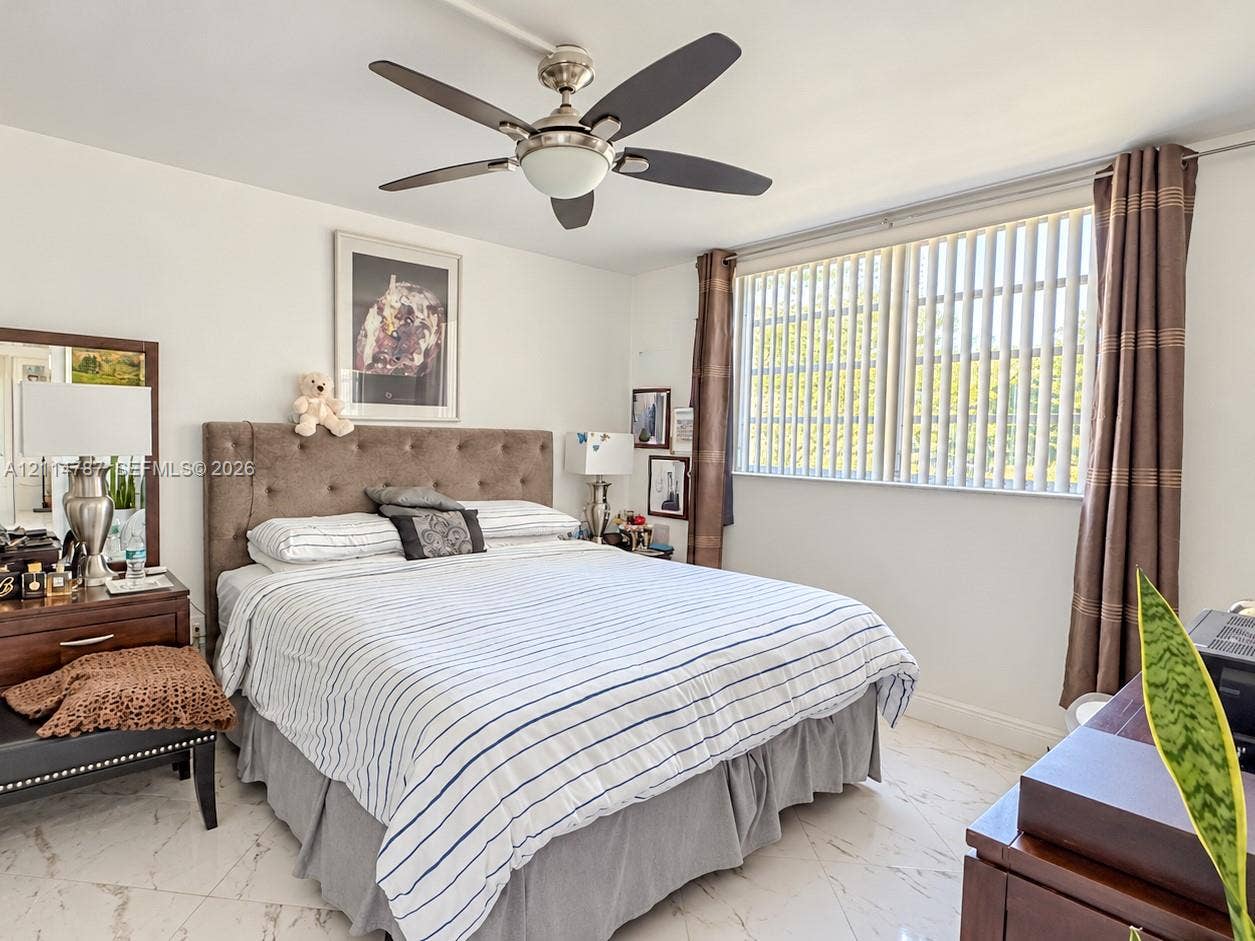 Polished stone flooring, five-blade ceiling fan with integrated lighting, and large window with vertical blinds