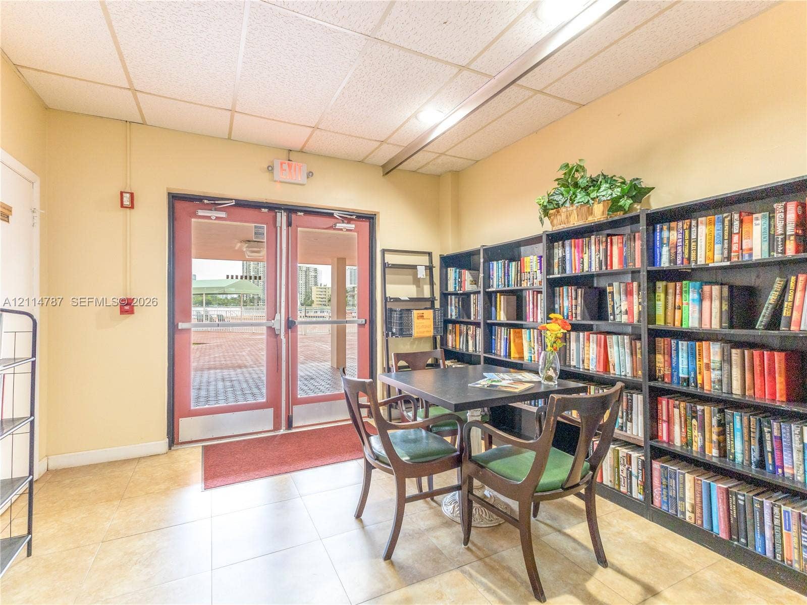 Common area featuring large-format tile flooring, double glass-paneled entry doors, and expansive floor-to-ceiling built-in shelving units