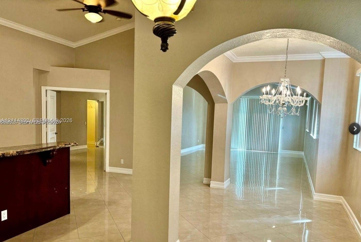 932 Falling Water Road, Weston, Weston, FL 33326 Interior featuring high ceilings, neutral wall tones, polished tile flooring, decorative arched architectural details, and crystal-style chandelier lighting