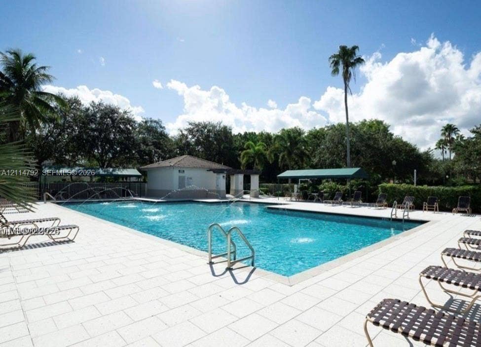 932 Falling Water Road, Weston, Weston, FL 33326 Swimming pool featuring water fountains, tiled decking, a shaded cabana, and mature perimeter landscaping