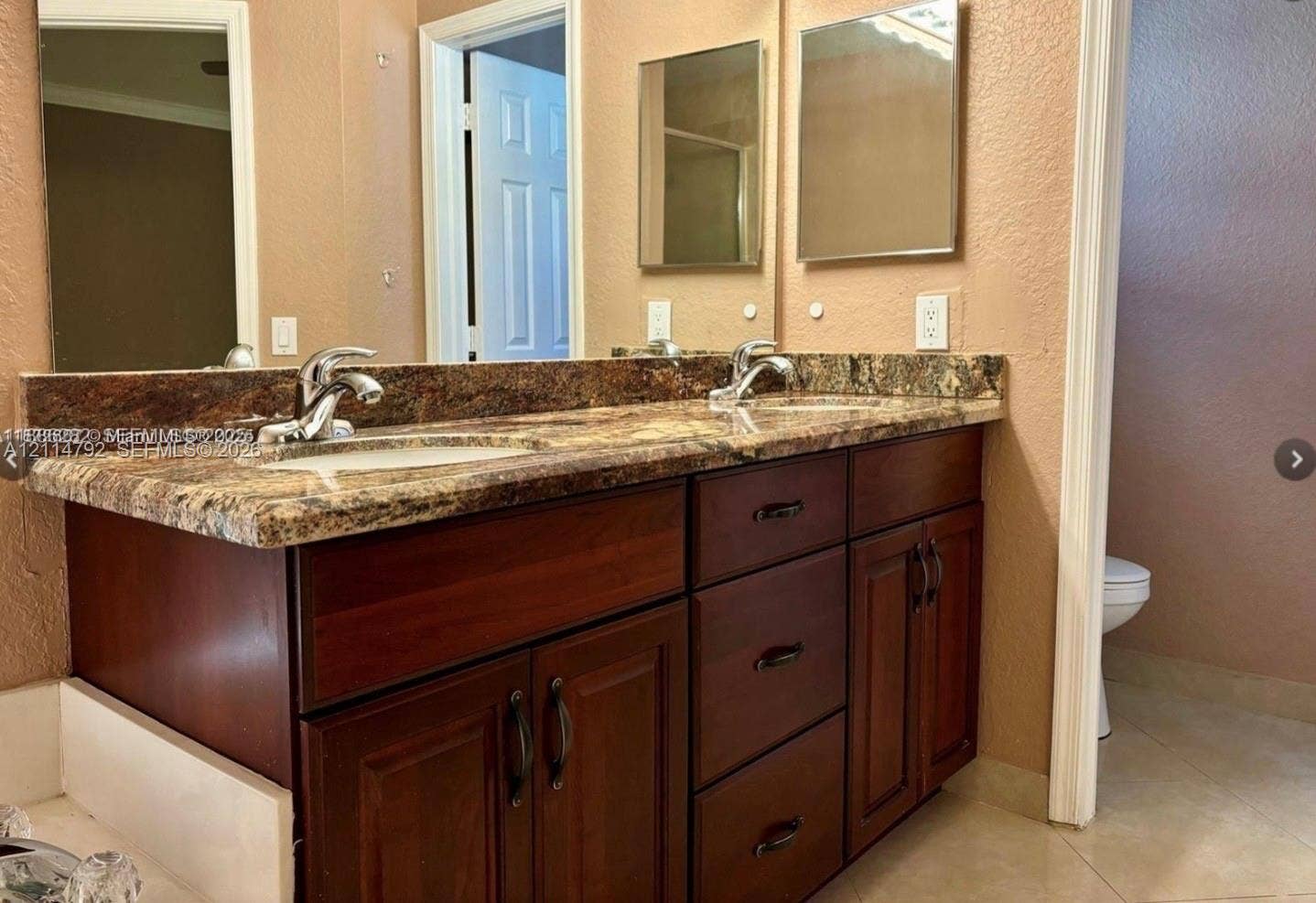 932 Falling Water Road, Weston, Weston, FL 33326 Double-sink vanity featuring dark wood-finish cabinetry, stone-patterned countertops, dual undermount basins with polished chrome faucets, and two wall-mounted mirrors