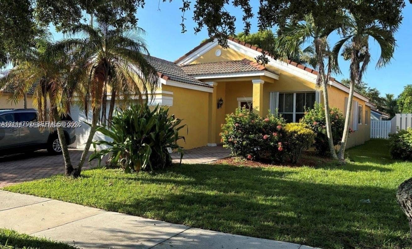 932 Falling Water Road, Weston, Weston, FL 33326 Single-story residence featuring a paved driveway, tiled roof, stucco exterior, covered entryway, and mature palm trees