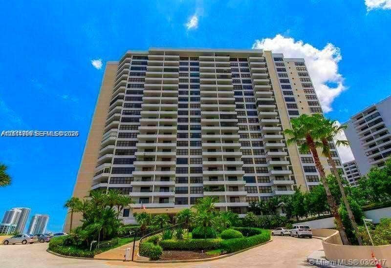 2500 Parkview Drive, #811, Hallandale Beach, Hallandale Beach, FL 33009 High-rise residential building featuring expansive private balconies, a paved arrival drive, and manicured landscaping with mature palm trees