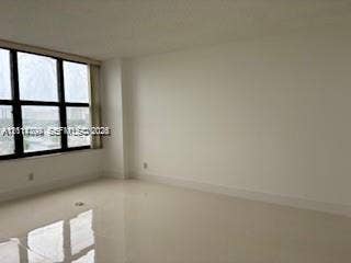 2500 Parkview Drive, #811, Hallandale Beach, Hallandale Beach, FL 33009 Neutral-toned interior space featuring polished tile flooring, white walls, and expansive windows with black frames
