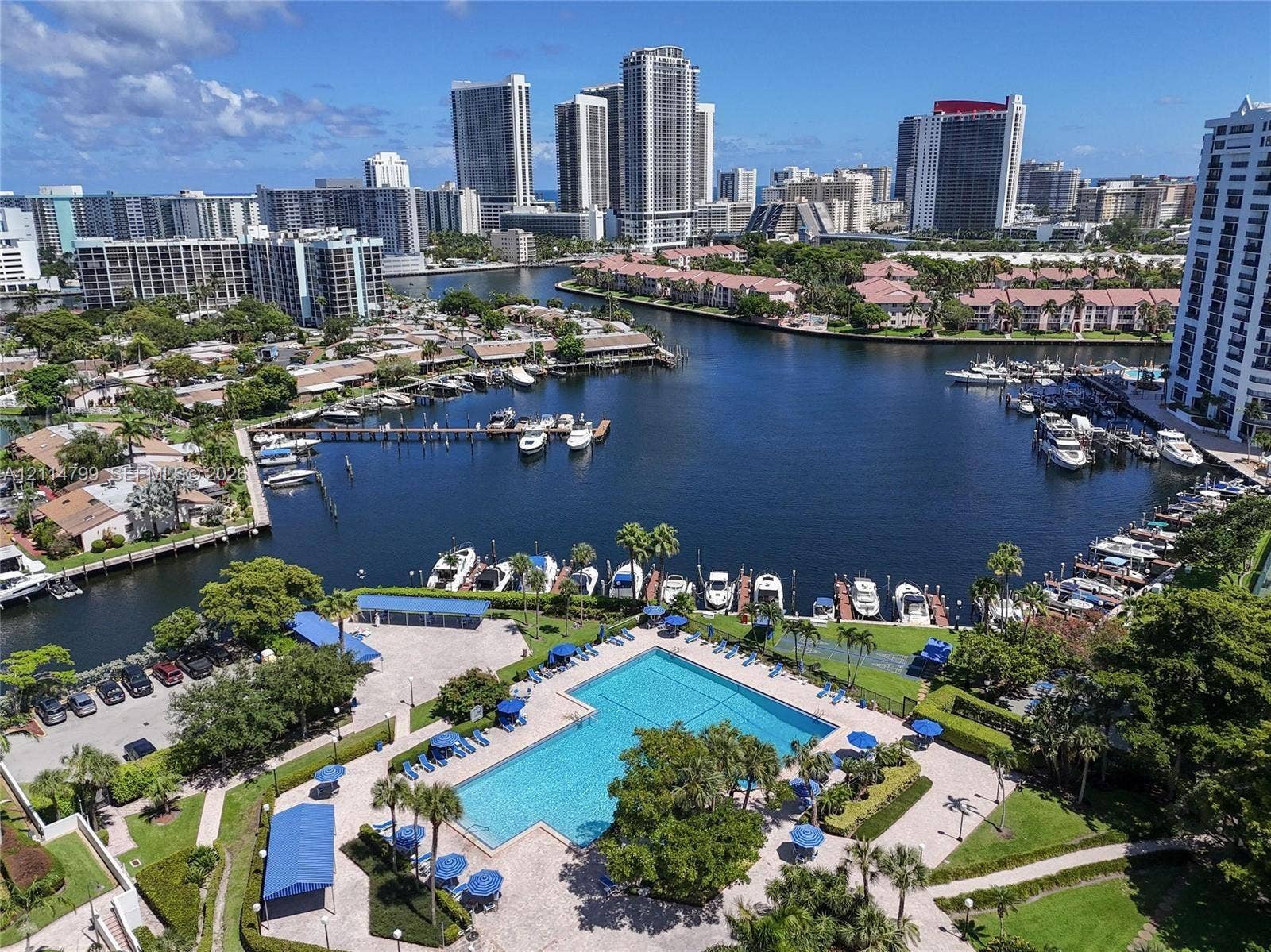 2500 Parkview Drive, #811, Hallandale Beach, Hallandale Beach, FL 33009 Rectangular swimming pool with paved decking, surrounding landscaping, marina access, and metropolitan skyline backdrop