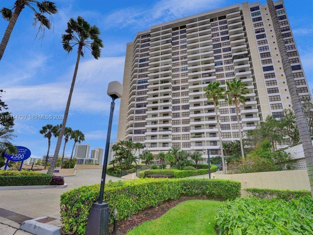 2500 Parkview Drive, #811, Hallandale Beach, Hallandale Beach, FL 33009 High-rise residential building featuring private balconies, expansive windows, manicured landscaping, and palm-lined exterior grounds
