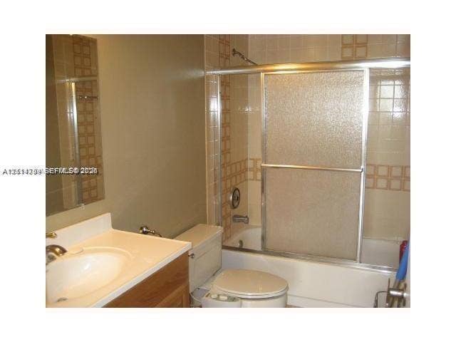 2500 Parkview Drive, #811, Hallandale Beach, Hallandale Beach, FL 33009 Bathroom featuring a wood-finish vanity, integrated sink, tub and shower combination with sliding glass doors, and decorative tile accents