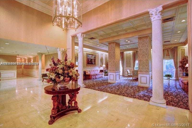 2500 Parkview Drive, #811, Hallandale Beach, Hallandale Beach, FL 33009 Grand entrance hall featuring polished stone flooring, ornate classical columns, recessed ceiling lighting, and a tiered hanging chandelier