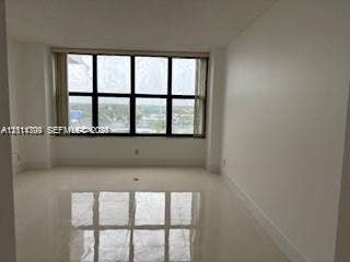 2500 Parkview Drive, #811, Hallandale Beach, Hallandale Beach, FL 33009 Neutral-toned interior space featuring polished tile flooring, smooth wall finishes, and expansive black-framed multi-pane windows