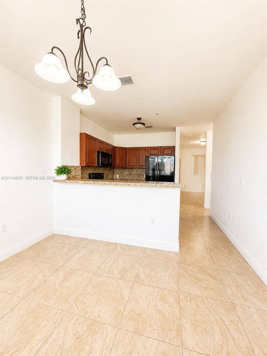 18130 NW 59th Avenue, #201, Hialeah, Hialeah, FL 33015 Kitchen featuring wood-finish cabinetry, stone-style countertops, tile flooring, and a decorative hanging light fixture