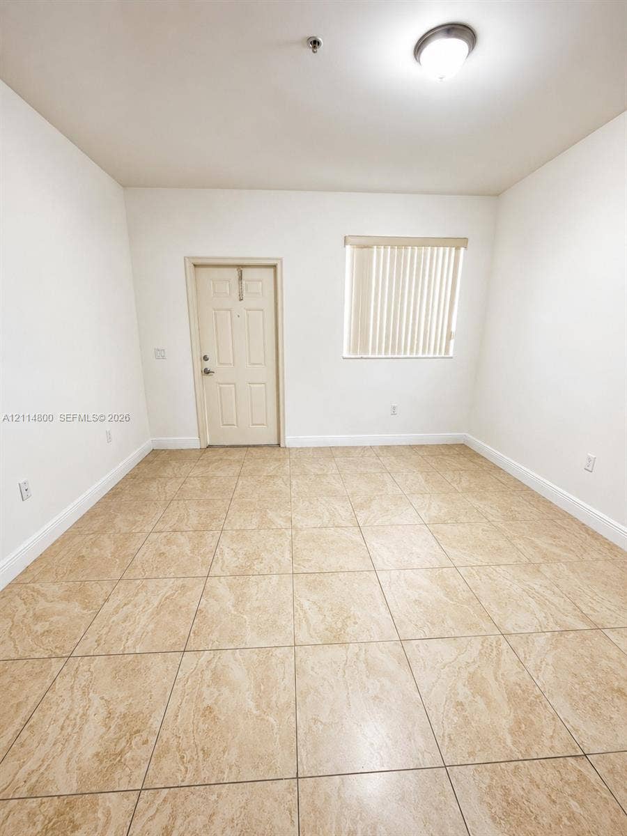 18130 NW 59th Avenue, #201, Hialeah, Hialeah, FL 33015 Interior space featuring neutral wall tones, large-format tile flooring, a window with vertical blinds, and a flush-mount ceiling light fixture