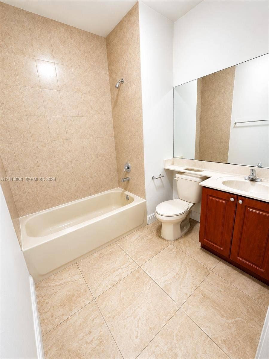 18130 NW 59th Avenue, #201, Hialeah, Hialeah, FL 33015 Bathroom featuring a tub-shower combination with floor-to-ceiling tile surround, large-format tile flooring, a wood-finish vanity with a solid-surface countertop, and a full-width wall-mounted mirror