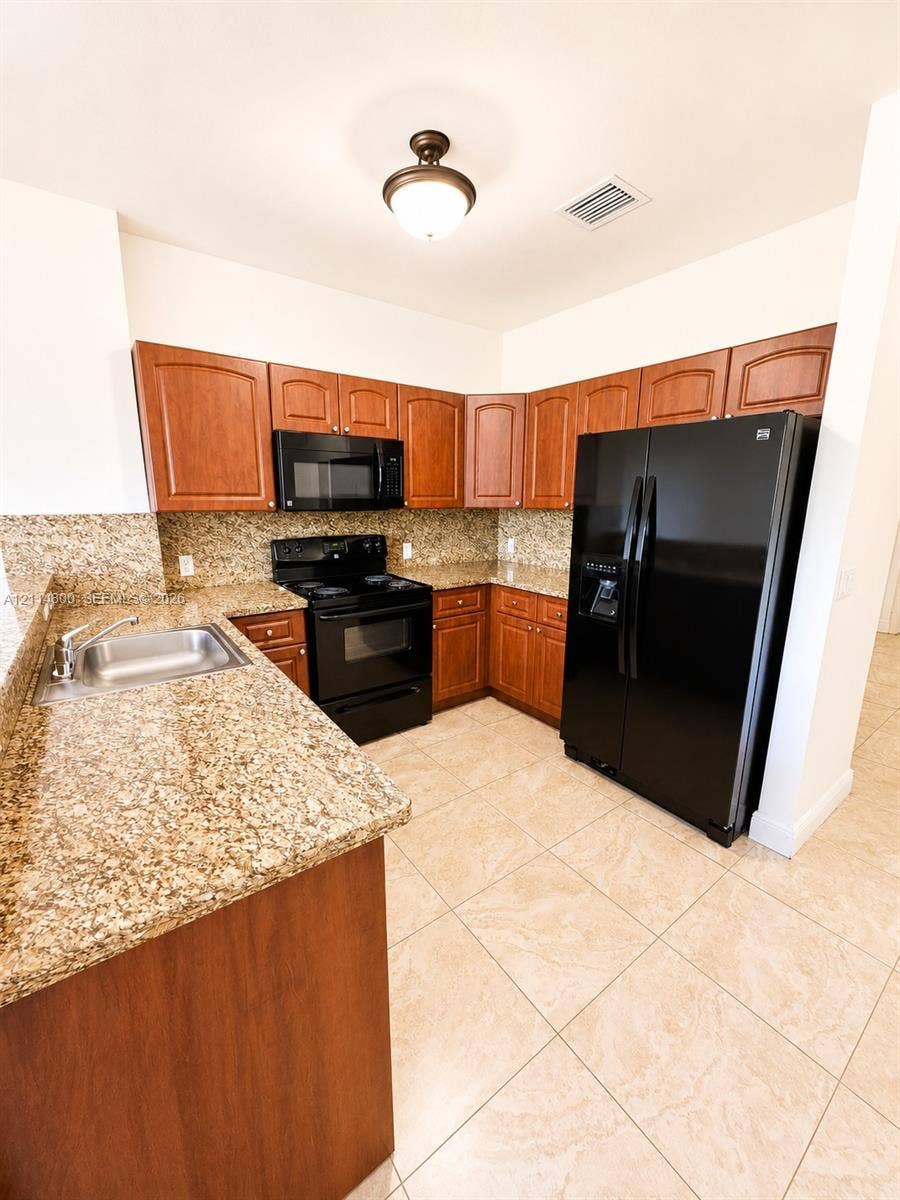 18130 NW 59th Avenue, #201, Hialeah, Hialeah, FL 33015 Kitchen featuring wood cabinetry, stone countertops, black appliances, tile flooring, and a drop-in stainless steel sink