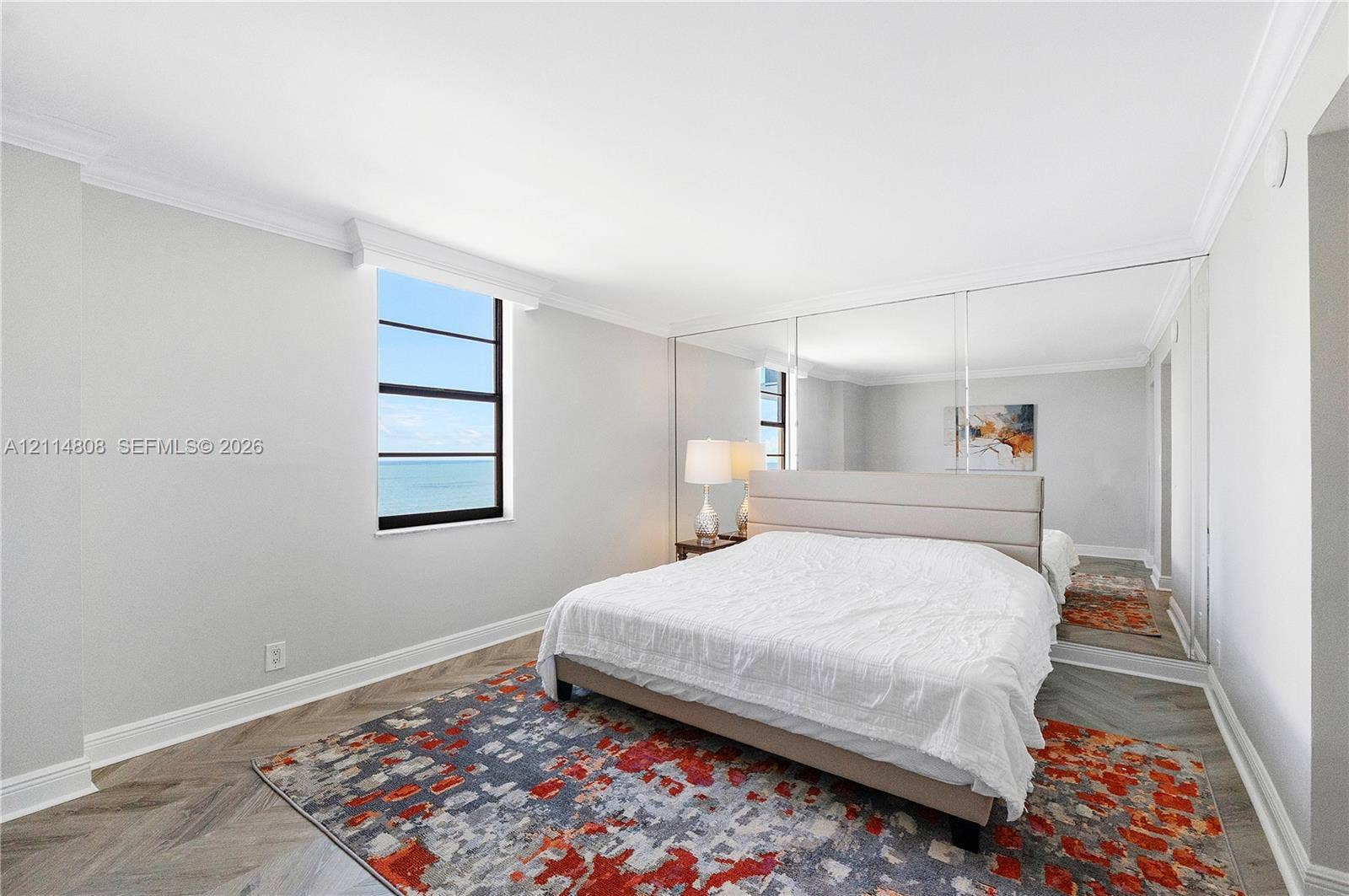 1000 S Ocean Boulevard, #16P, Pompano Beach, Pompano Beach, FL 33062 Herringbone patterned wood-finish flooring, floor-to-ceiling wall mirrors, crown molding, and a window framing a water horizon