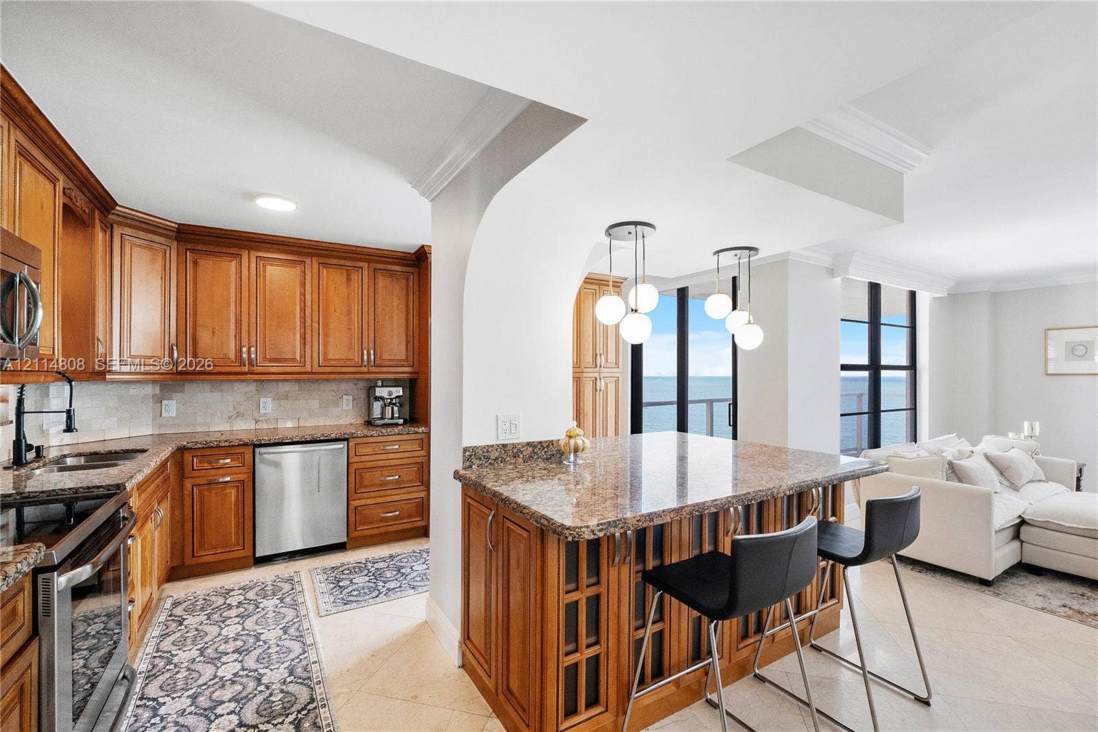 1000 S Ocean Boulevard, #16P, Pompano Beach, Pompano Beach, FL 33062 Kitchen featuring wood cabinetry, stone countertops, stone tile backsplash, stainless steel appliances, and multi-light pendant fixtures over a breakfast bar