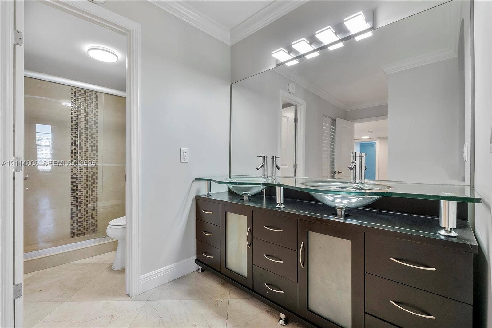 1000 S Ocean Boulevard, #16P, Pompano Beach, Pompano Beach, FL 33062 Double vanity with vessel sinks, glass countertop, dark wood-finish cabinetry, full-width mirror, and walk-in shower with mosaic tile accent