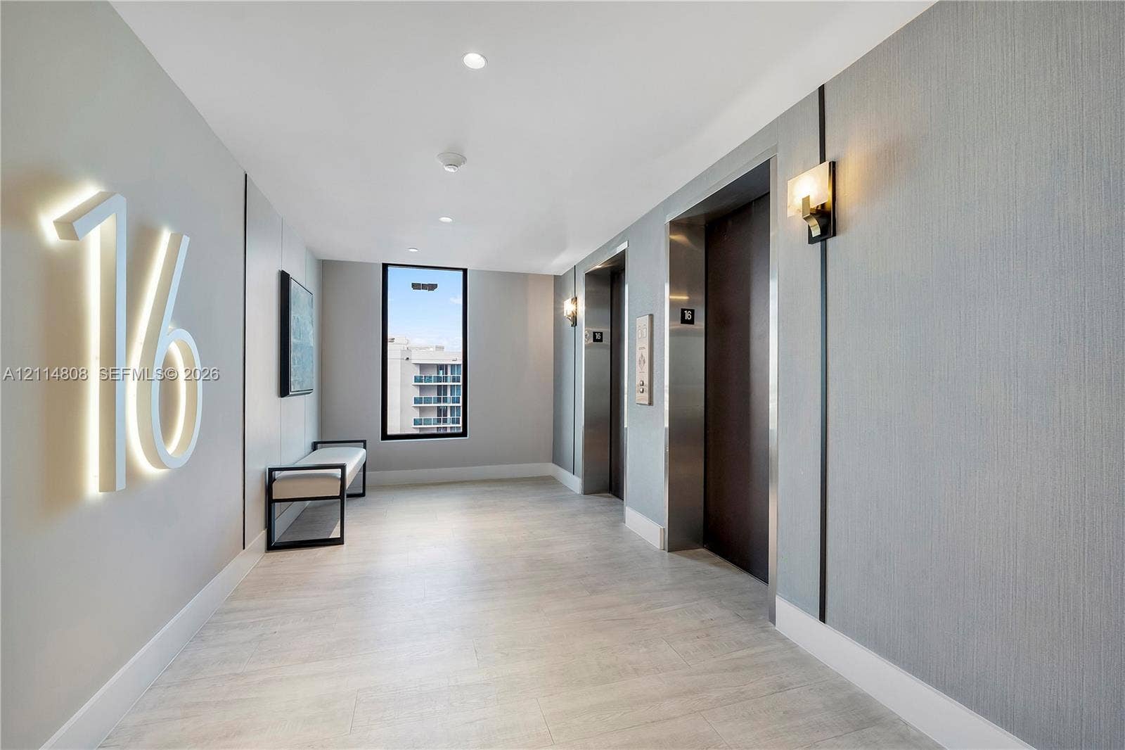 1000 S Ocean Boulevard, #16P, Pompano Beach, Pompano Beach, FL 33062 Elevator lobby featuring illuminated wall signage, recessed ceiling lighting, textured wall coverings, dual elevator access with metallic finishes, and wood-finish flooring