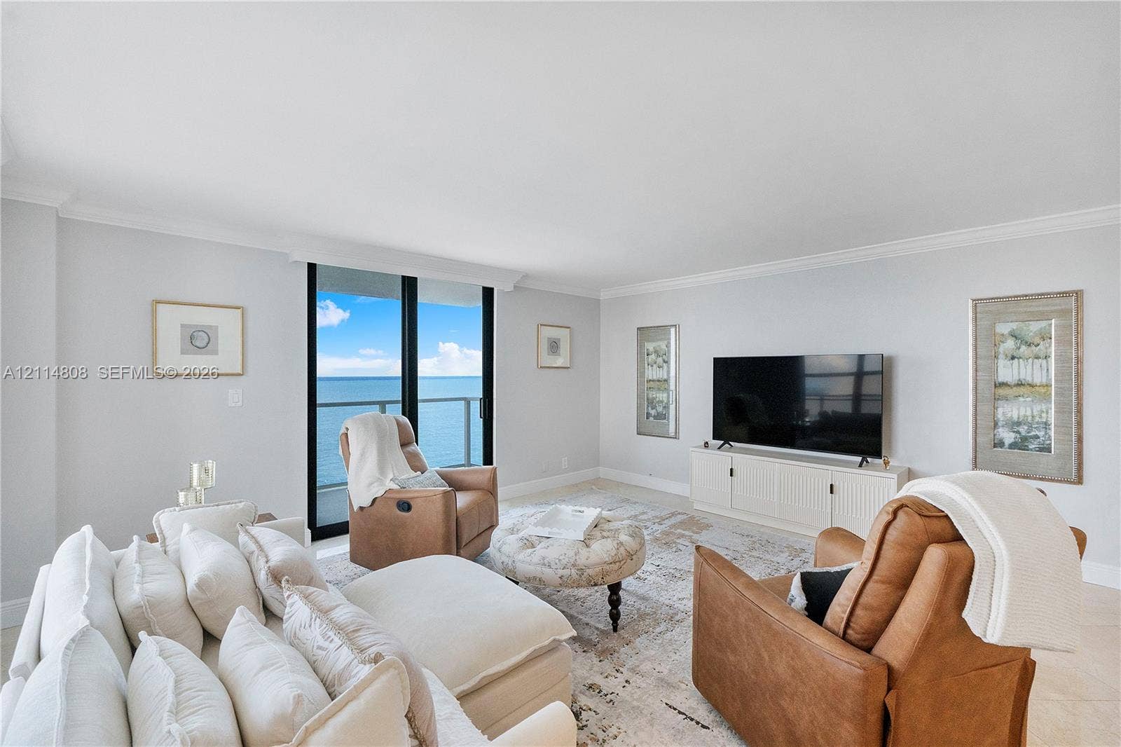1000 S Ocean Boulevard, #16P, Pompano Beach, Pompano Beach, FL 33062 Living area featuring light-toned tile flooring, crown molding, and floor-to-ceiling glass sliding doors leading to an exterior balcony with water scenery