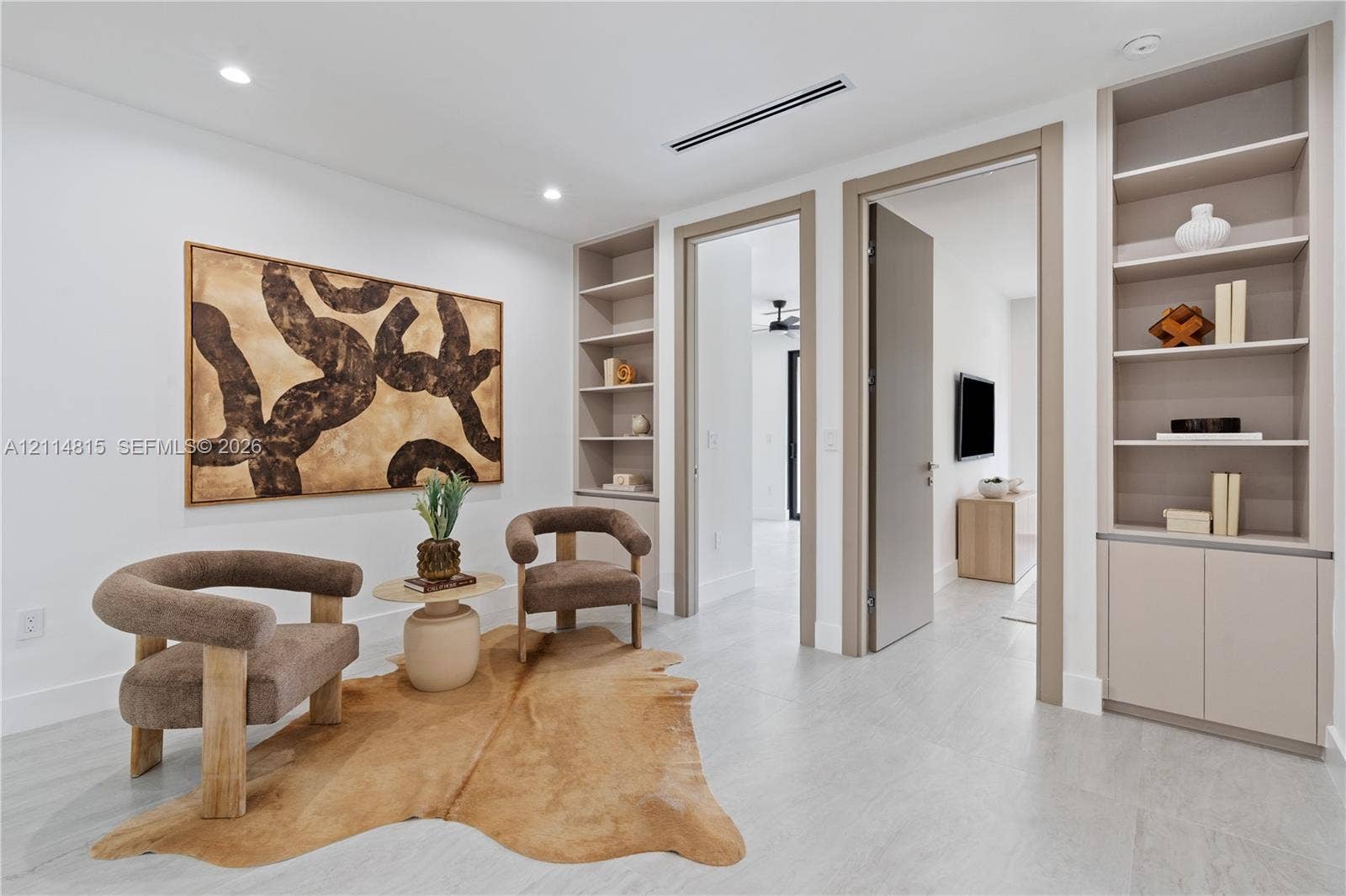 Built-in cabinetry featuring recessed shelving and lower storage cabinets, complemented by light-toned, large-format tile flooring and recessed ceiling lighting