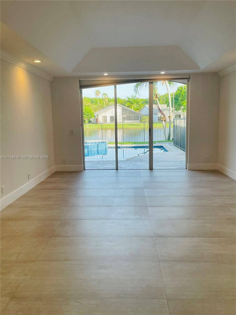 1952 Water Ridge Drive, #1952, Weston, Weston, FL 33326 Tray ceiling with recessed lighting, large-format tile flooring, and floor-to-ceiling sliding glass doors opening to a swimming pool and water frontage