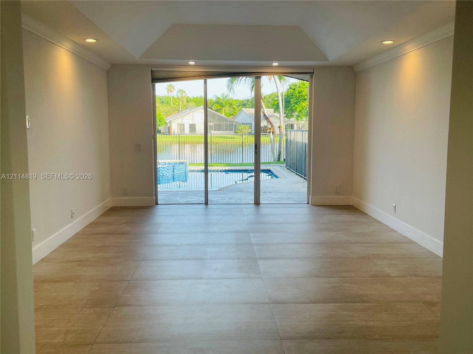 1952 Water Ridge Drive, #1952, Weston, Weston, FL 33326 Tray ceiling, large-format tile flooring, recessed lighting, and expansive sliding glass doors opening to a private pool and water-front lot