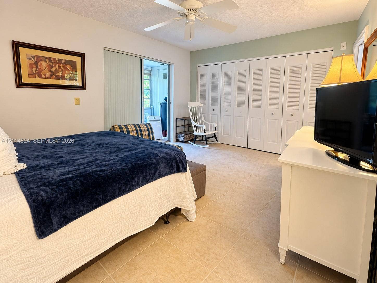 563 Durham T, #563, Deerfield Beach, FL 33442 Bedroom featuring tile flooring, sliding glass patio doors, a ceiling fan with integrated lighting, and multiple louvered-style closet doors
