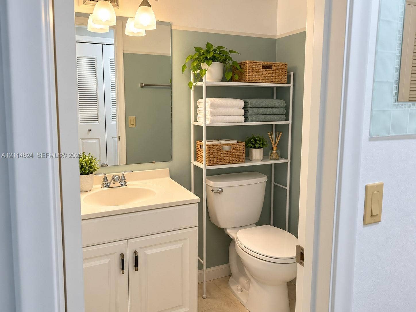 563 Durham T, #563, Deerfield Beach, FL 33442 Bathroom featuring a white vanity cabinet, integrated countertop basin, three-light wall-mounted fixture, and louvered-style closet doors