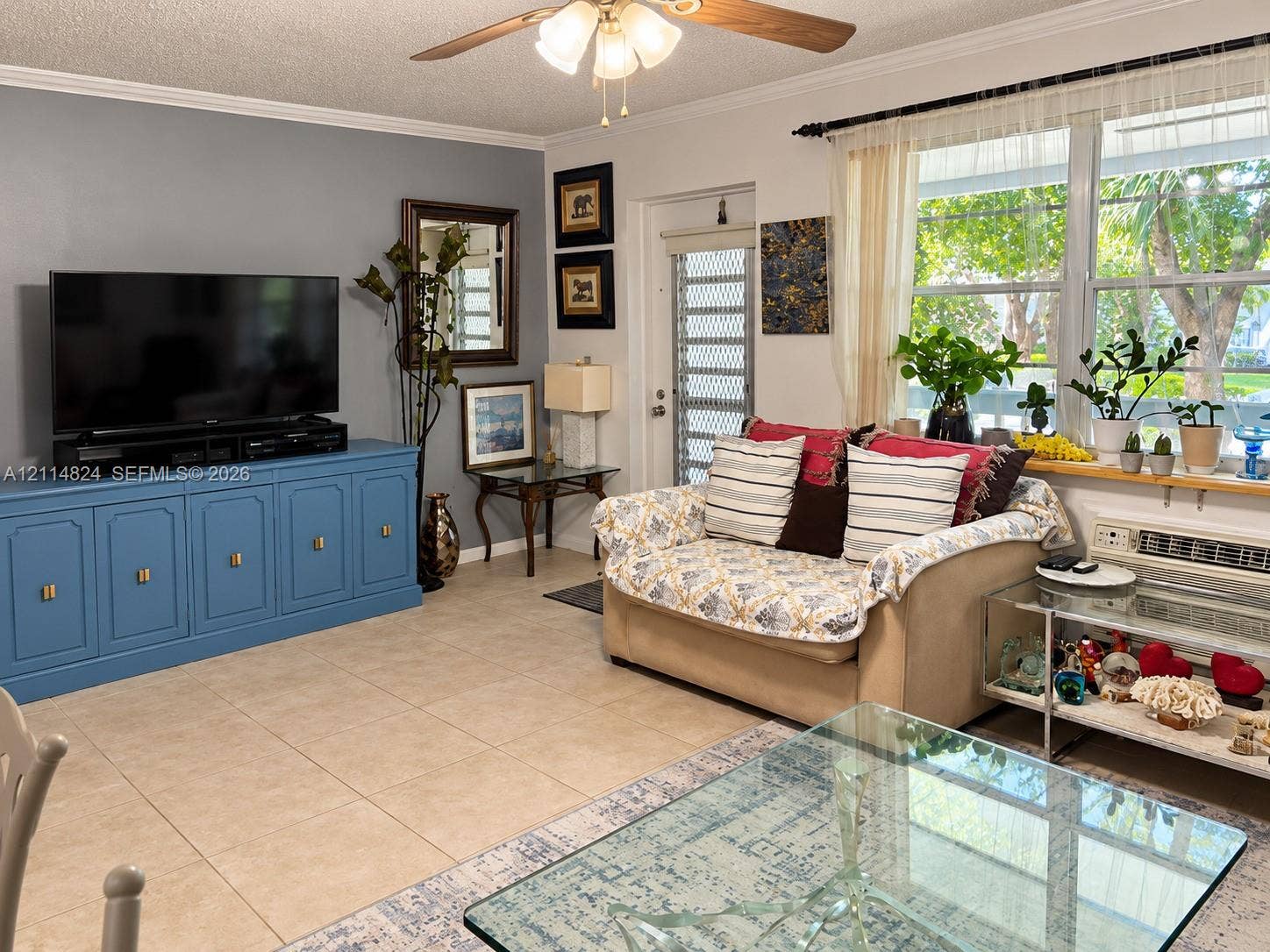 563 Durham T, #563, Deerfield Beach, FL 33442 Living area featuring large-format tile flooring, built-in blue storage cabinetry, ceiling fan with integrated lighting, and a metal security door