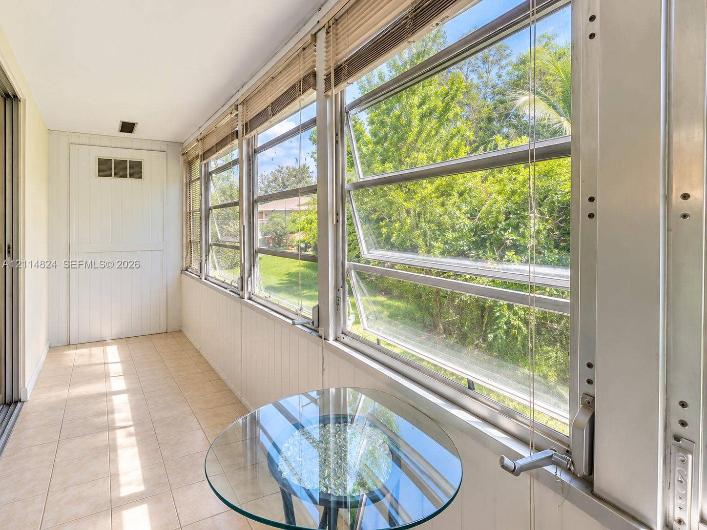 563 Durham T, #563, Deerfield Beach, FL 33442 Enclosed sunroom featuring ceramic tile flooring, vertical wall paneling, and multiple awning-style windows