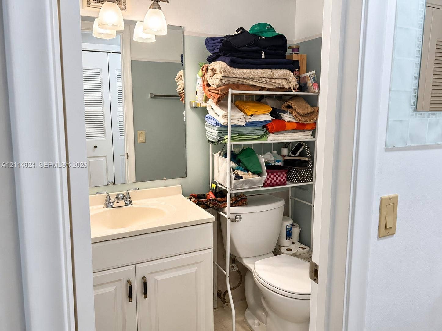 563 Durham T, #563, Deerfield Beach, FL 33442 Bathroom featuring a vanity with an integrated sink and basin, white shaker-style cabinetry, and a wall-mounted mirror with integrated three-bulb lighting fixture