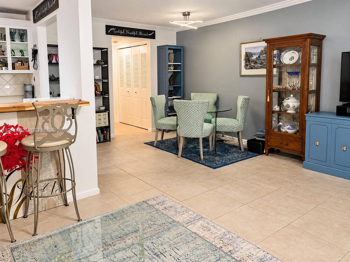 563 Durham T, #563, Deerfield Beach, FL 33442 Neutral-toned tile flooring, built-in breakfast bar with a wood-finish countertop, recessed shelving, and a modern geometric ceiling light fixture