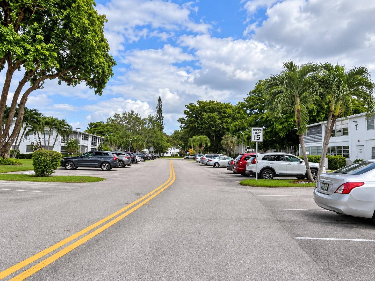 563 Durham T, #563, Deerfield Beach, FL 33442 Asphalt parking area featuring designated spaces and mature landscaping with palm trees and shade trees