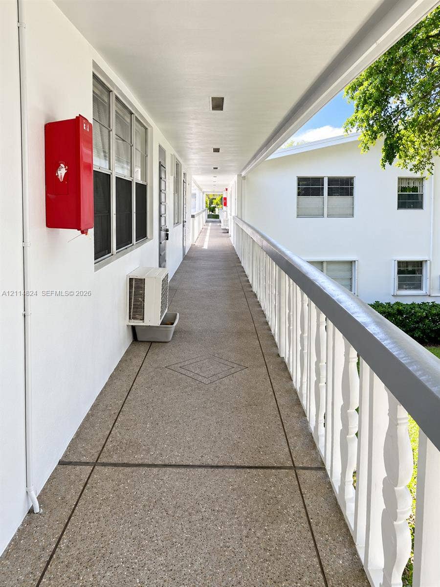 563 Durham T, #563, Deerfield Beach, FL 33442 Covered exterior walkway featuring exposed aggregate flooring, geometric tile inlay, and a solid balustrade railing