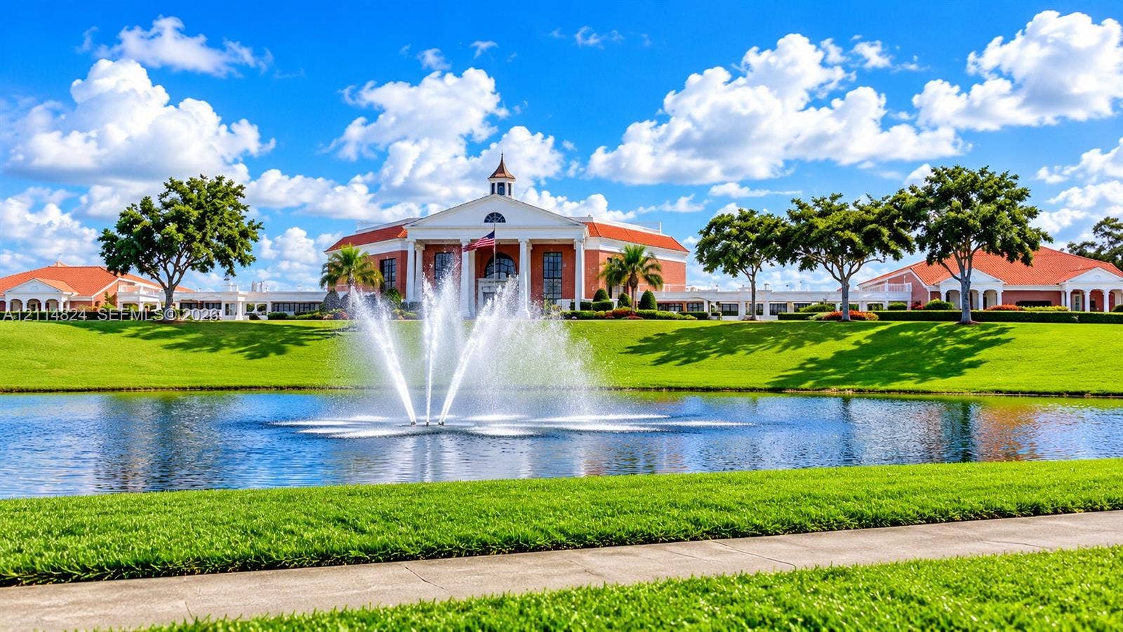 563 Durham T, #563, Deerfield Beach, FL 33442 Colonial-style architecture featuring a central cupola and multi-columned portico, accented by a centered water fountain, surrounding pond, and expansive lawn