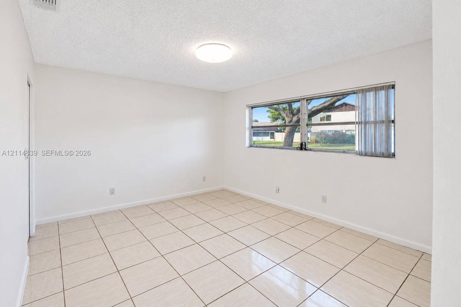 3000 NW 5th Terrace, #131, Pompano Beach, Pompano Beach, FL 33064 Neutral interior space featuring polished tile flooring, light-toned walls, a flush-mount ceiling light, and a large window with horizontal blinds