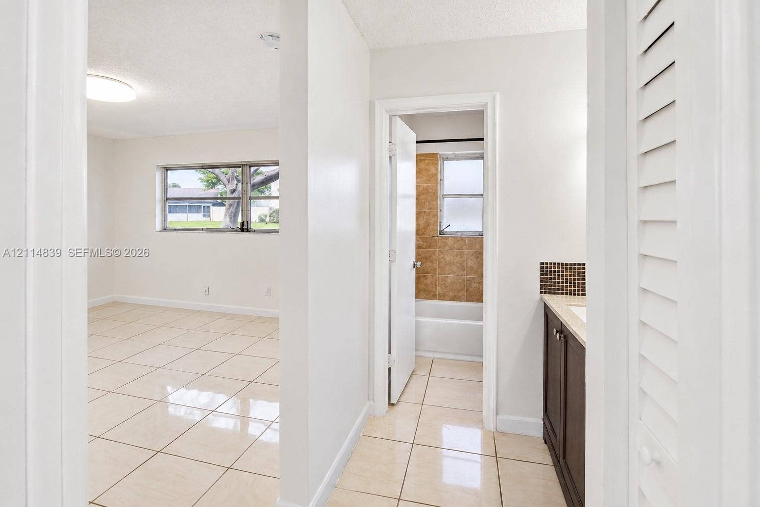 3000 NW 5th Terrace, #131, Pompano Beach, Pompano Beach, FL 33064 Large-format tile flooring, vanity with a stone countertop, square mosaic tile backsplash, louvered closet door, and tub-shower combination with textured wall tiling
