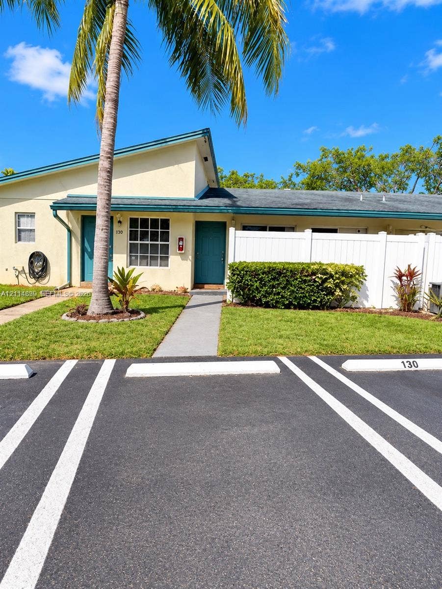 3000 NW 5th Terrace, #131, Pompano Beach, Pompano Beach, FL 33064 Exterior facade featuring a single-story design, dual entry doors, private white vinyl fencing, concrete walkways, and designated asphalt parking