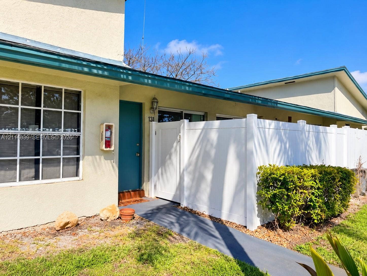 3000 NW 5th Terrace, #131, Pompano Beach, Pompano Beach, FL 33064 Stucco exterior featuring a white vinyl privacy fence, grid-pattern windows, and a solid-color entryway door