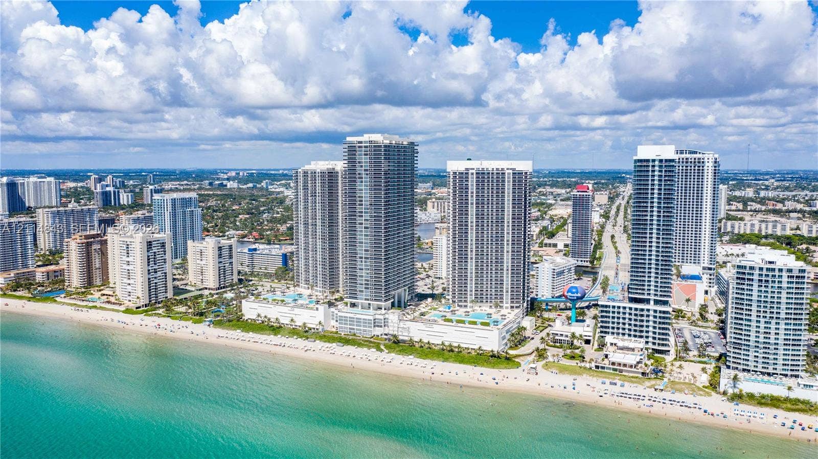 Aerial perspective of a coastal high-rise development featuring direct oceanfront access, exterior balconies, swimming pool decks, and proximity to the Atlantic shoreline