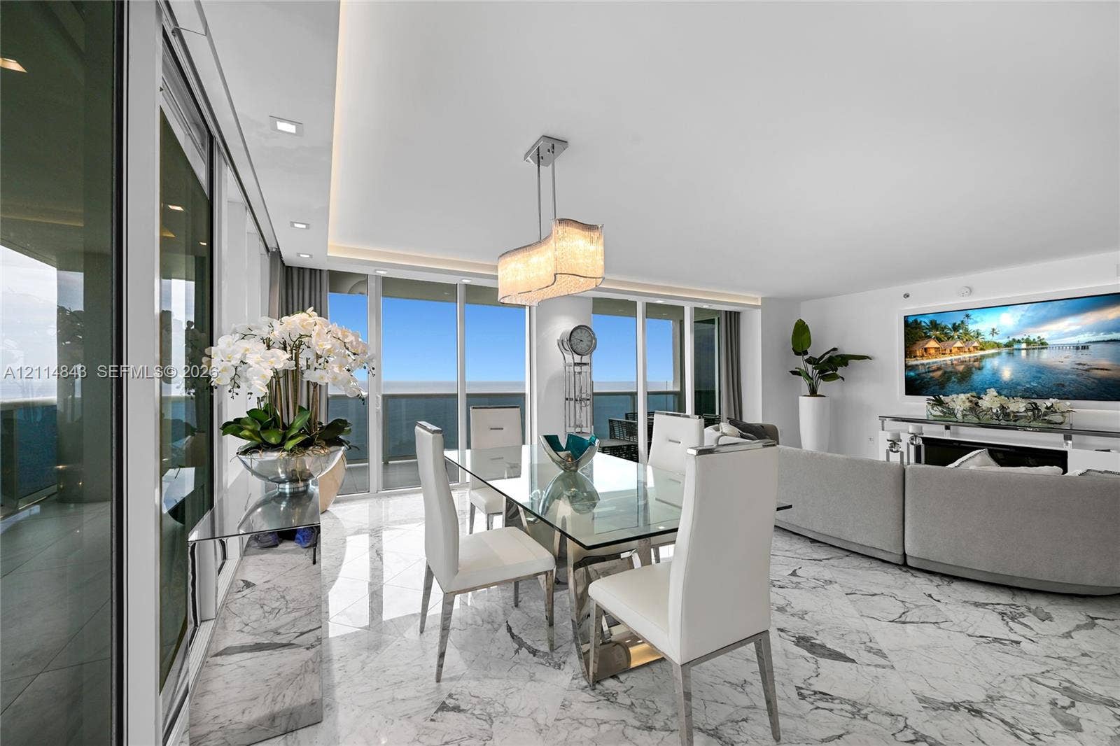 Open-concept living space featuring stone flooring, floor-to-ceiling glass panel doors, recessed ceiling lighting, and a custom built-in stone console