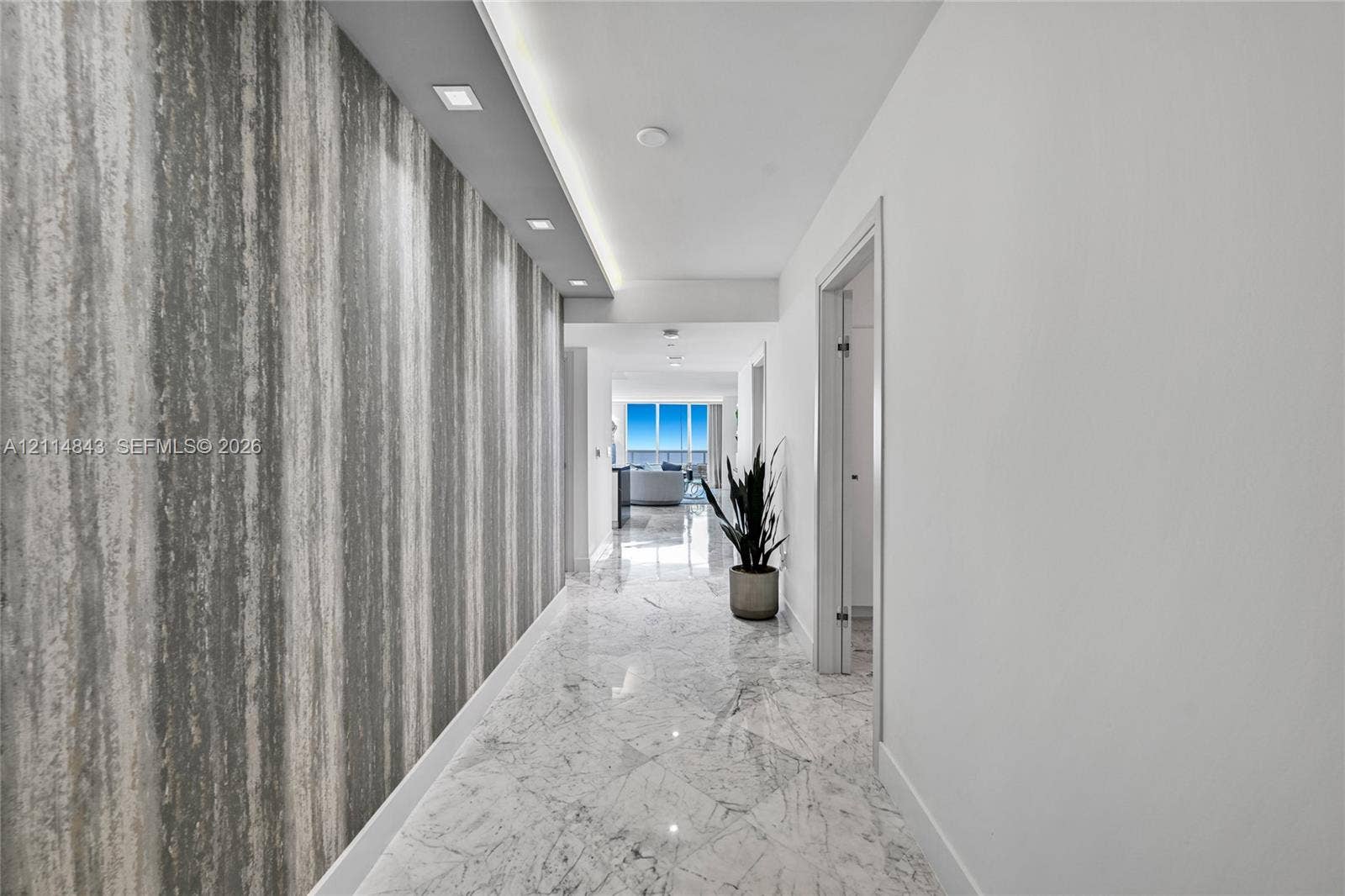 Hallway featuring stone-finish flooring, a decorative textured accent wall, and recessed architectural ceiling lighting