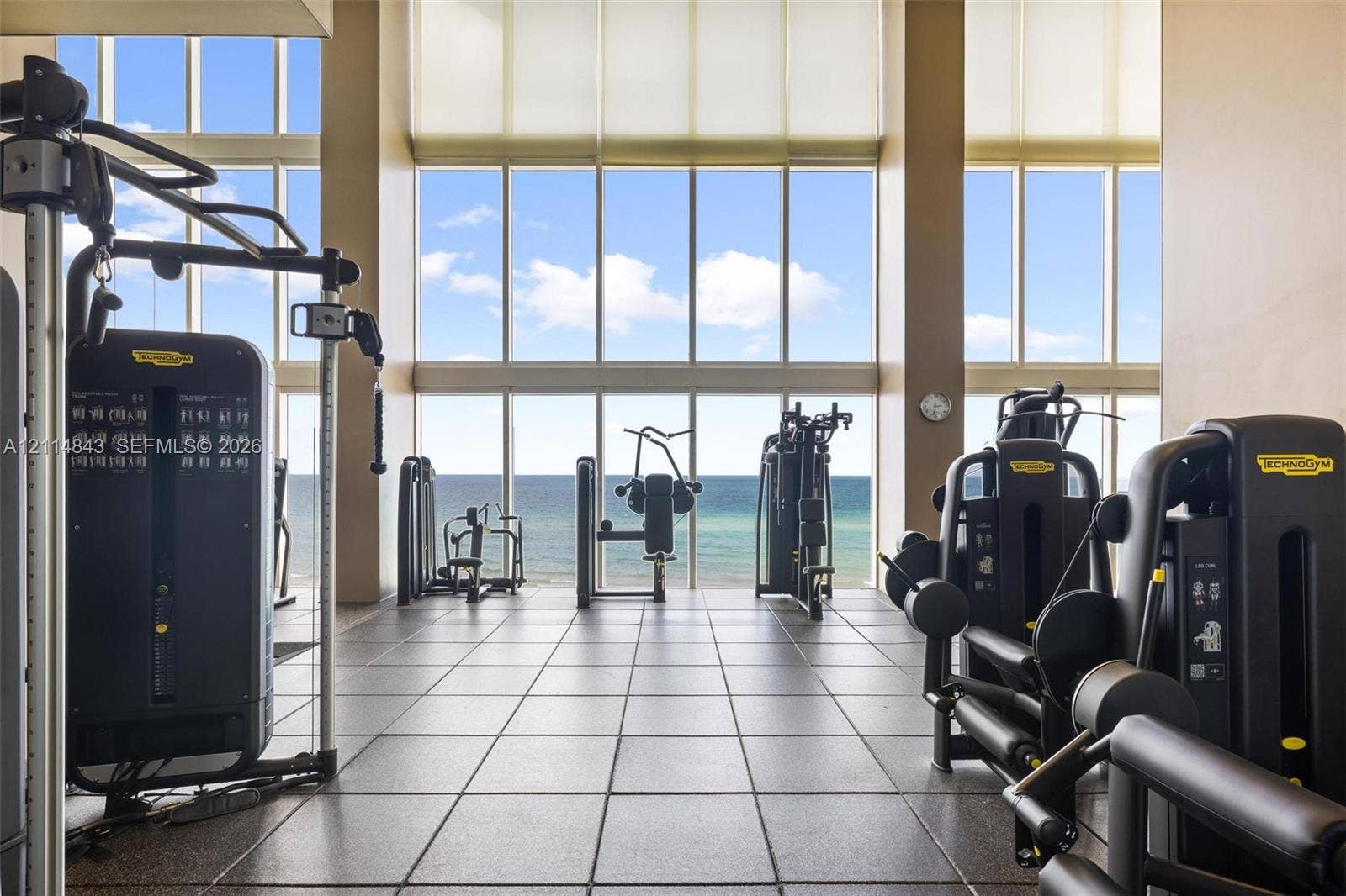 Fitness center featuring floor-to-ceiling windows, large-format tile flooring, and direct ocean exposure