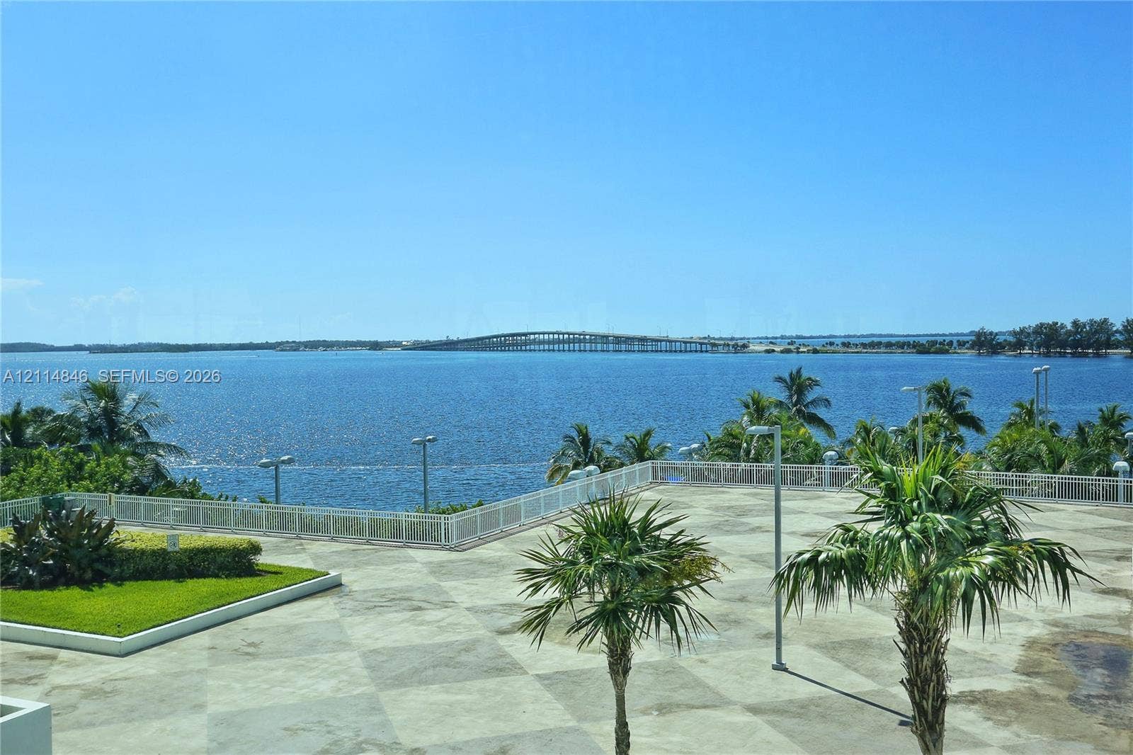2101 Brickell Avenue, #601, Miami, Miami, FL 33129 Expansive outdoor terrace featuring stone-tiled flooring, white perimeter fencing, integrated landscaping, and prominent water and bridge scenery