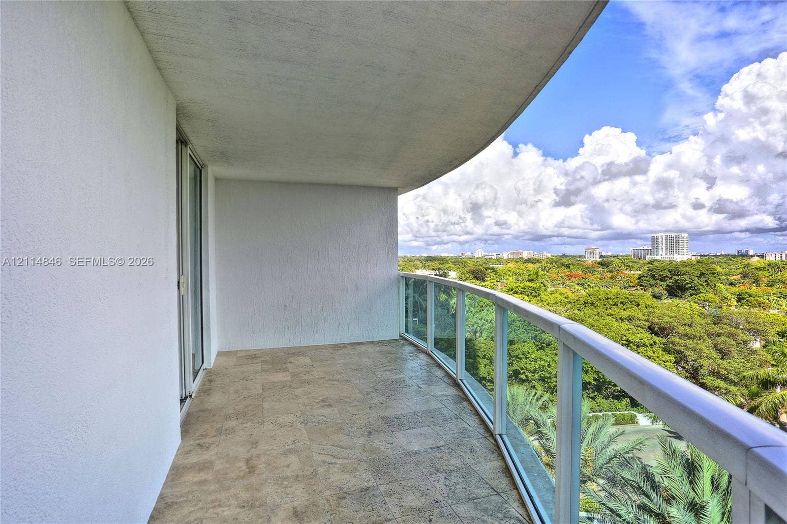 2101 Brickell Avenue, #601, Miami, Miami, FL 33129 Covered balcony featuring stone-finish flooring, a curved concrete ceiling, and a glass-paneled railing