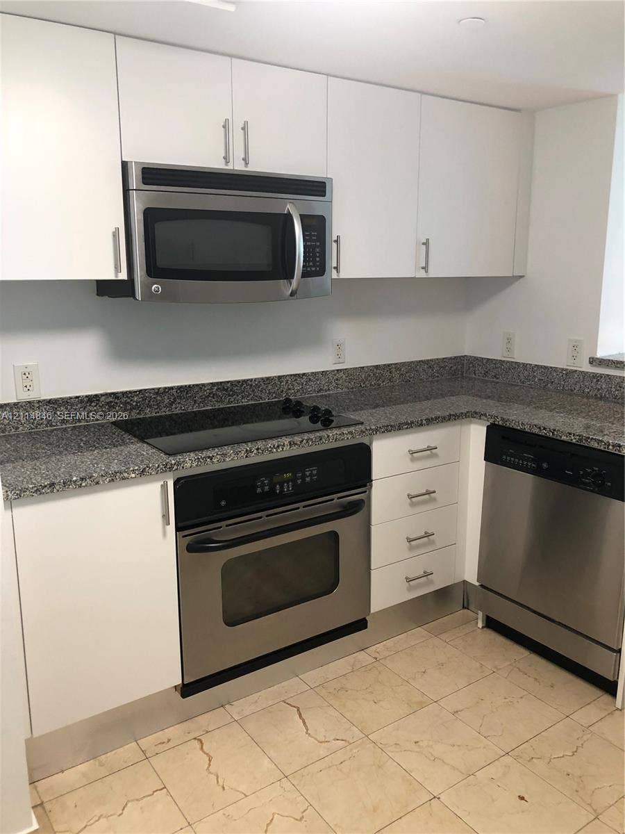 2101 Brickell Avenue, #601, Miami, Miami, FL 33129 Kitchen featuring white flat-panel cabinetry, stone countertops, stainless steel appliances, and tile flooring