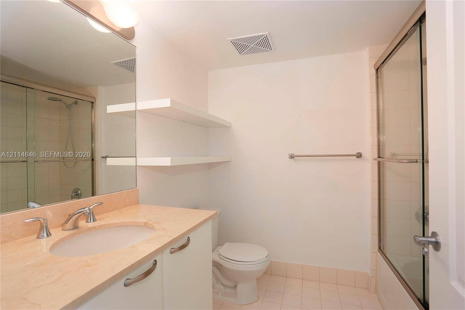 2101 Brickell Avenue, #601, Miami, Miami, FL 33129 Bathroom featuring a vanity with a neutral-toned countertop and integrated sink, large wall-mounted mirror, white built-in shelving, and a glass-enclosed shower with tiled surround