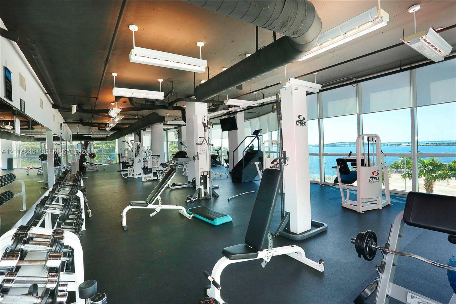 2101 Brickell Avenue, #601, Miami, Miami, FL 33129 Fitness center featuring floor-to-ceiling windows, industrial-style exposed ceiling, rubberized flooring, and expansive water exposure