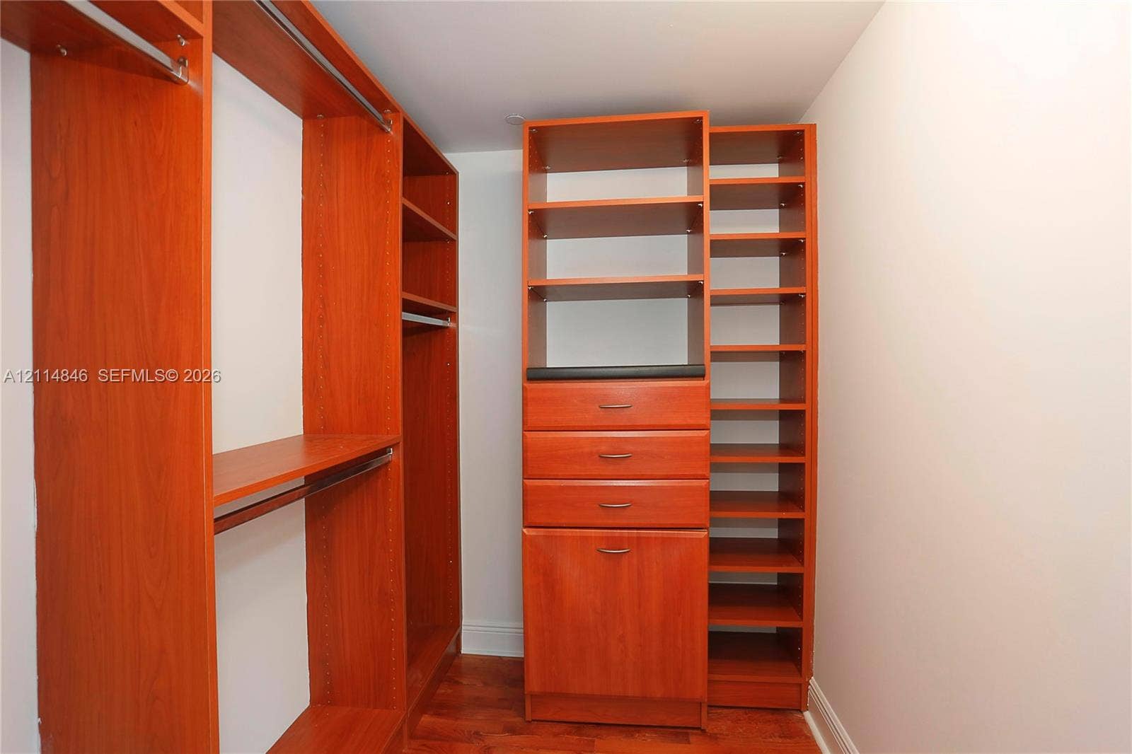 2101 Brickell Avenue, #601, Miami, Miami, FL 33129 Custom closet featuring wood-finish cabinetry, integrated shelving, multiple storage drawers with metal hardware, and wood-finish flooring